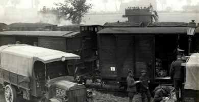 greyscale photo of vehicles beside train